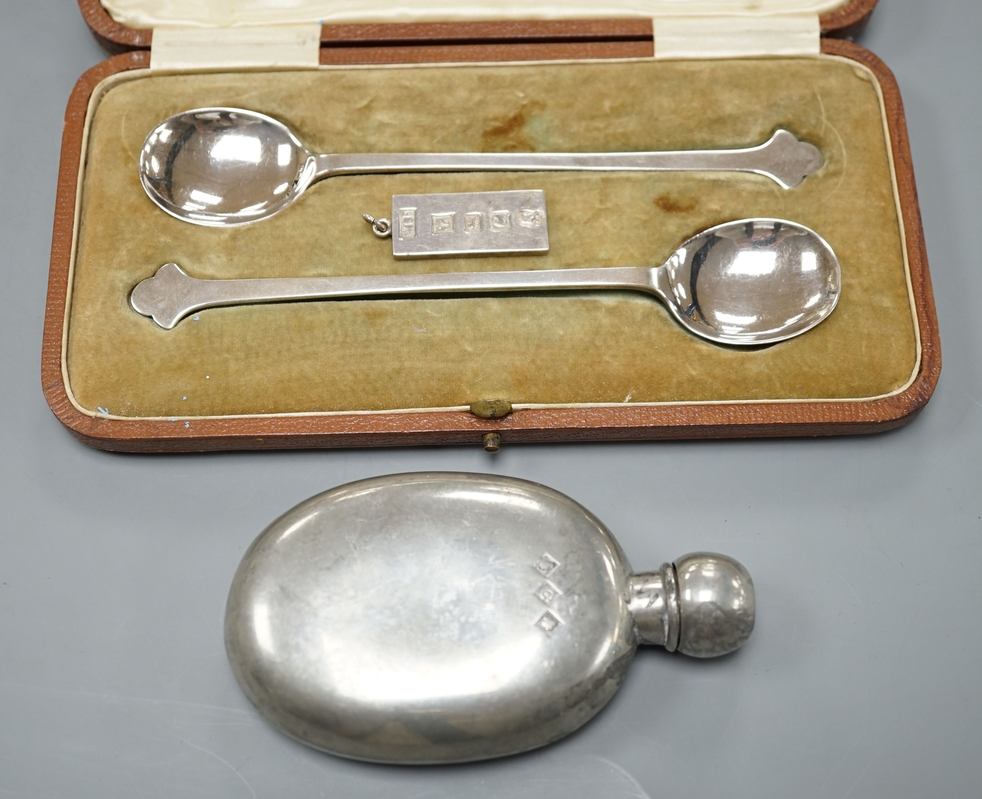 A cased pair of George V silver preserve spoons, Sheffield 1911, 36 grams, an ingot pendant, 15 grams and a pewter pocket flask